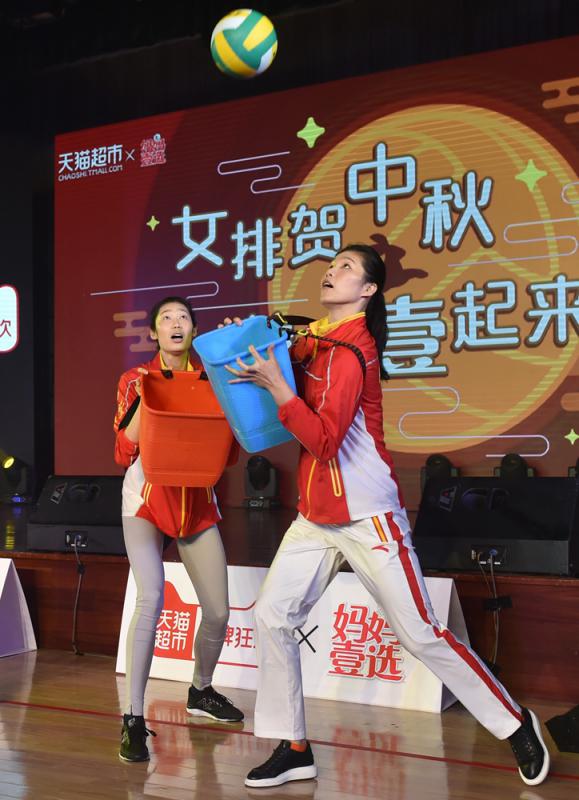 图:中国女排队员徐云丽(右)与朱婷参加用塑胶桶接排球的互动游戏