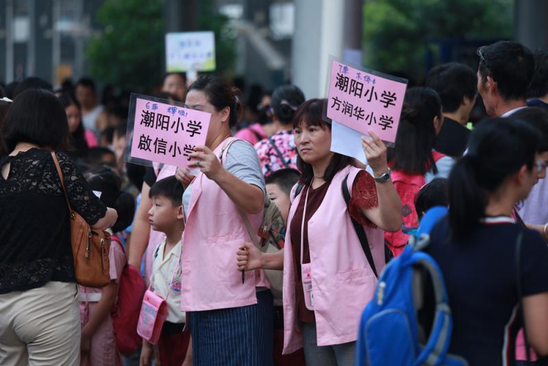 图:保姆公司工作人员手举指示牌,召集跨境学童排队\大公报记者黄