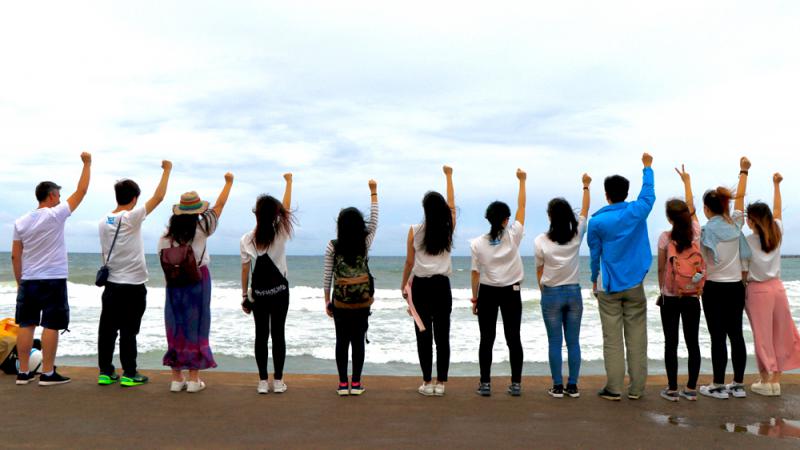 图:香港传媒学子们学漫画「海贼王」桥段,站在海边举手高呼拍照