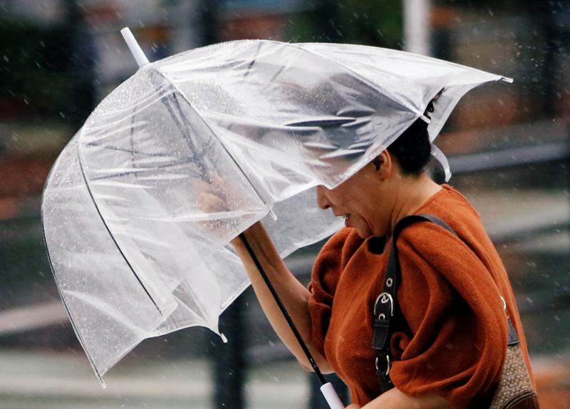 图:东京市民28日在风雨中艰难行走\路透社