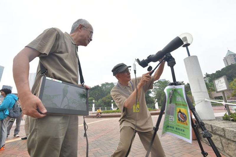 图:梁厚键(右)改装观鸟设备,让多人同时透过流动荧幕观鸟交流,增添